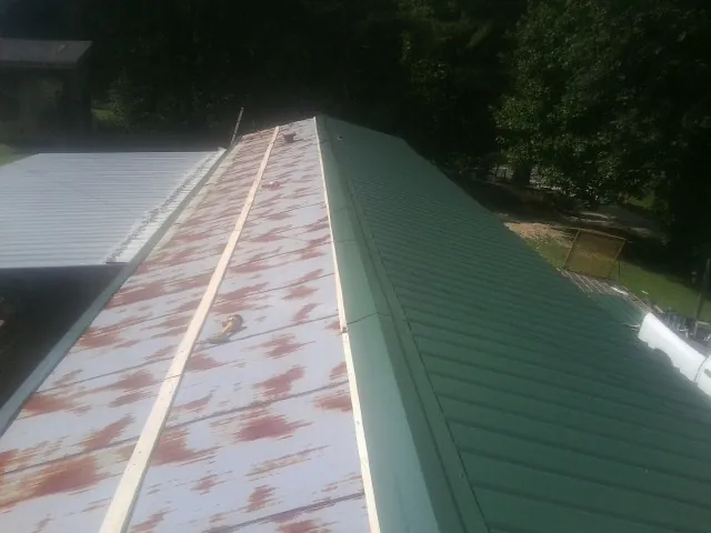 Old rusted panels beside newly installed green metal roofing — Wind Damage Roof Repair by Roofing Brothers in Chapman