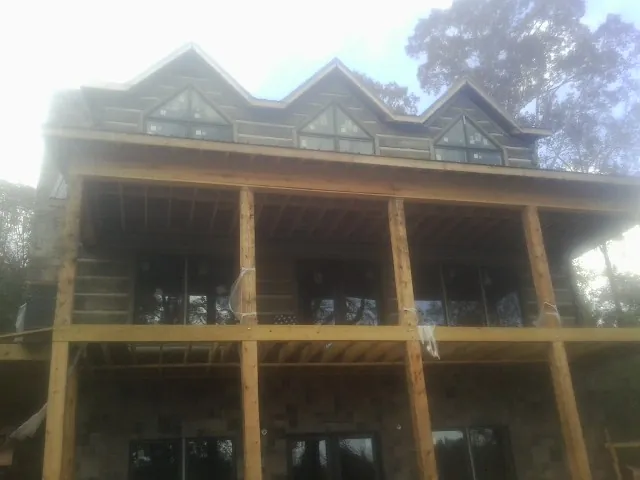 Dormers and porch framing on a large log home under construction — Roof Coating work by our crew in Chapman