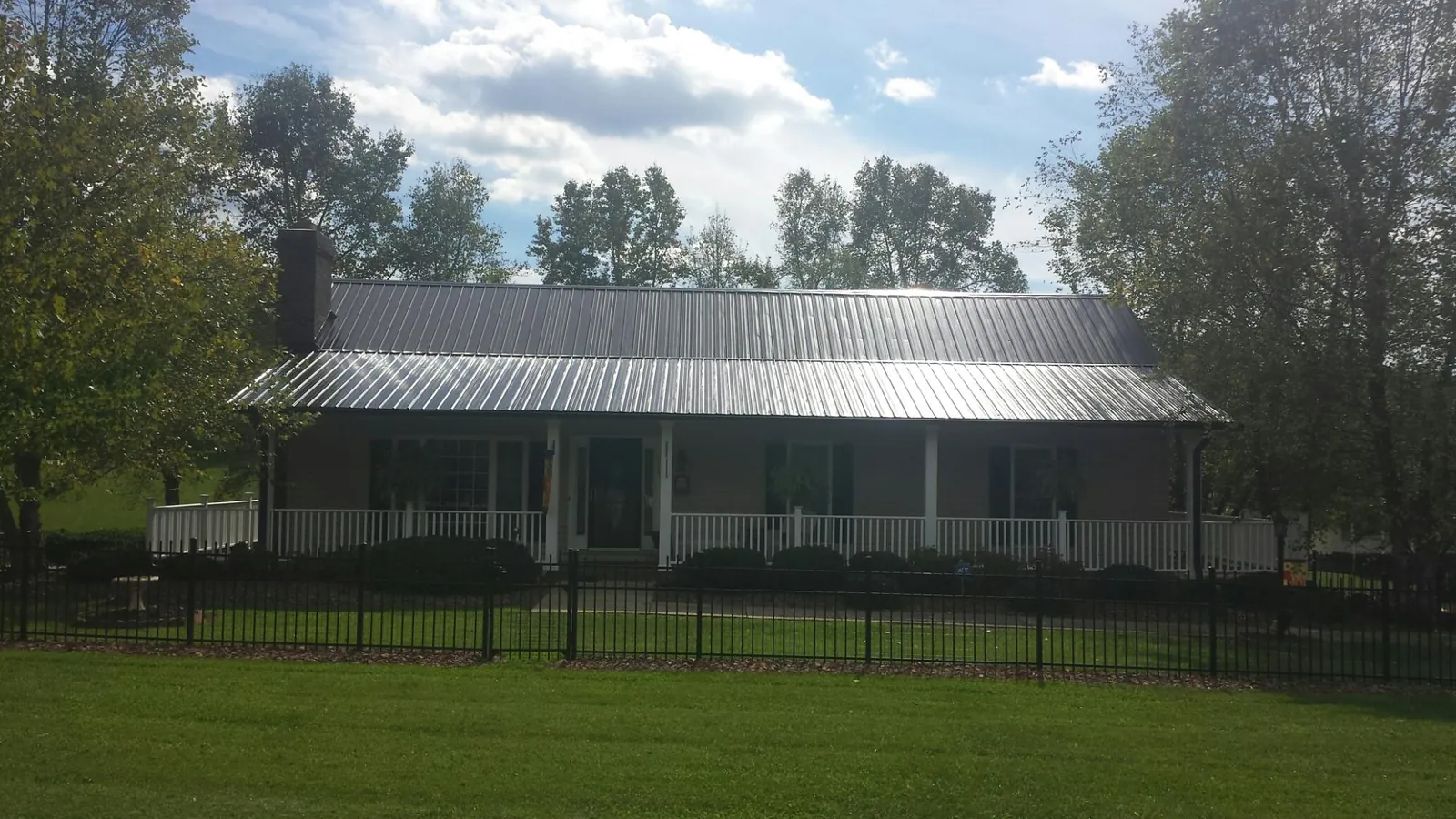 Gray metal roof on a brick ranch with a full width front porch — Gutter Guard Installation work by our crew in Chapman