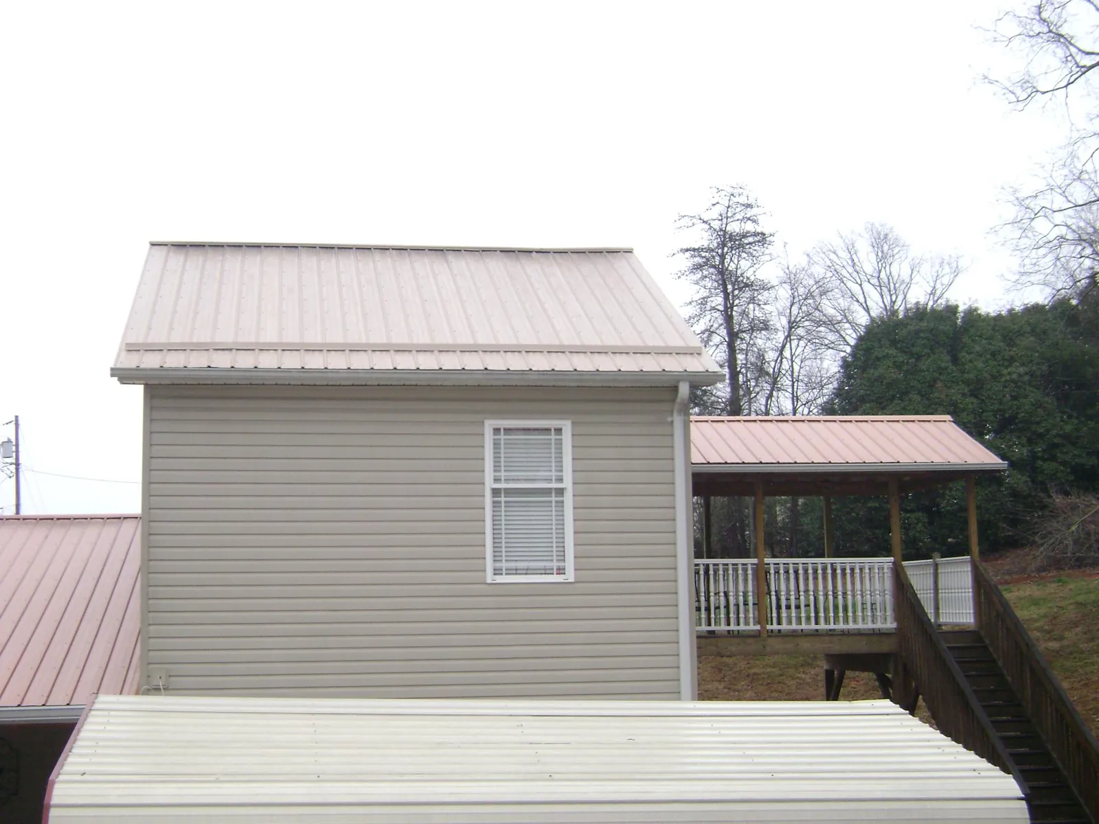 Tan metal roofs on a two story addition and attached porch, from a Roof Replacement job in Chapman