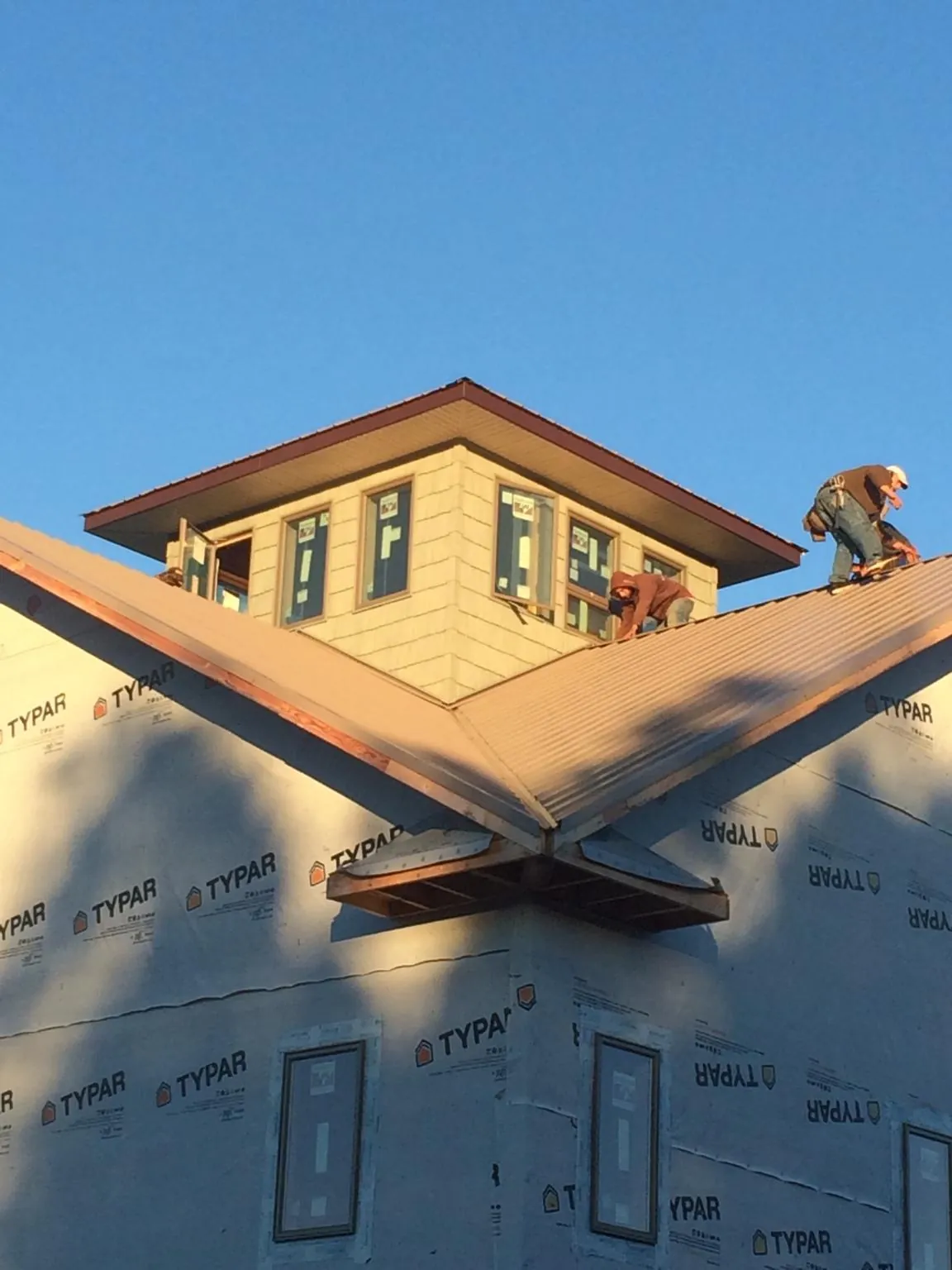 Roofers working around a rooftop cupola on a new metal roof at sunset — Roof Waterproofing in Chapman by Roofing Brothers